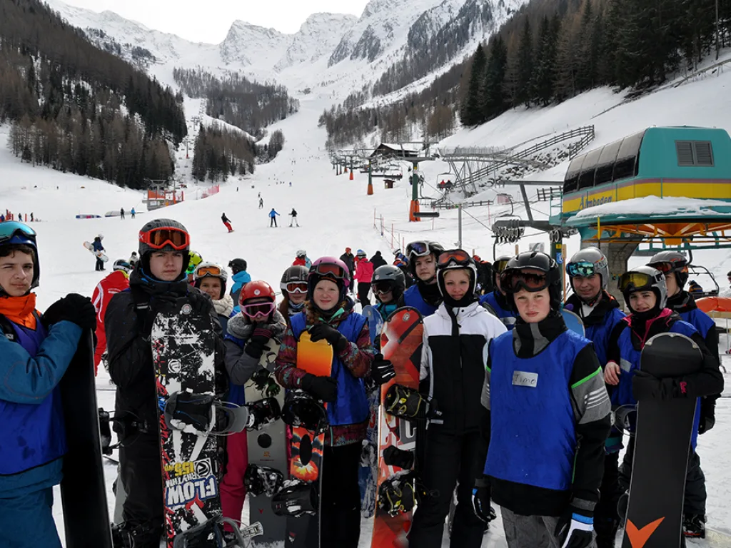 Große Gruppe mit Snowboards und Helmen wartet an der Talstation.